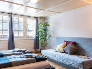 A hotel room with a bed, a sofa, a potted plant, and a window with curtains. - Apartment  by Interhome (Zurich)