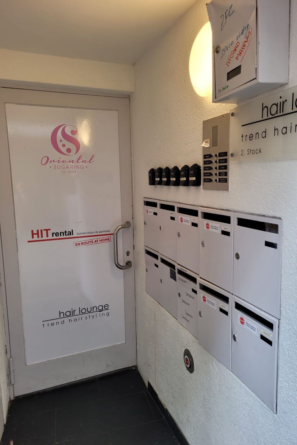 Ein Hotel Eingang mit einer Tür, auf der 'Oriental Sugaring' und 'HIT Vermietung Ferienwohnungen Stadt' steht.