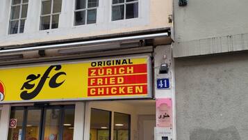 Ein Gebäude mit einem Schild für 'Original Zurich Fried Chicken' und einem Schild für 'Hair Lounge'.