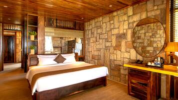 A wooden-paneled bedroom with a stone wall, a bed, a nightstand, and a mirror.