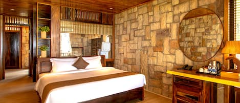 A wooden-paneled bedroom with a stone wall, a bed, a nightstand, and a mirror.