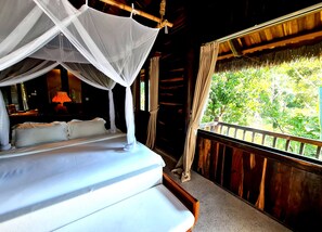 A bed with a canopy, a nightstand with a lamp, and a view of greenery outside. - Ocean Bay Resort & Spa Phu Quoc (Phu Quoc)