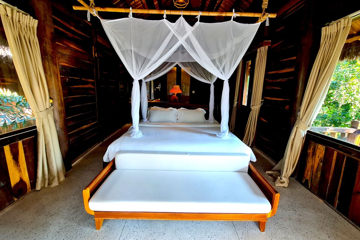 A bed with a canopy in a wooden room with curtains.