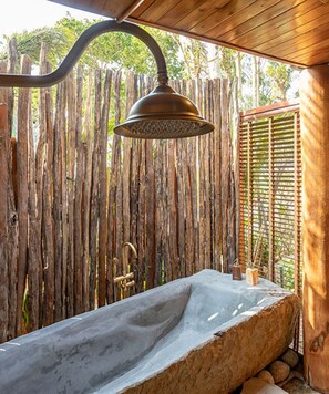A stone bathtub under a metal showerhead, surrounded by a wooden fence and a wooden structure. - Ocean Bay Resort & Spa Phu Quoc (Phu Quoc)