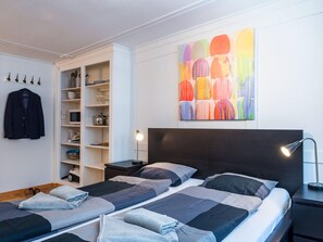 Ein Schlafzimmer mit zwei Betten, einem Kleiderschrank, einem Gemälde und einem Kleiderständer.