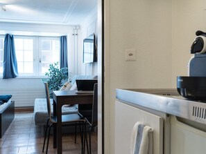 A compact living space with a kitchenette, a dining area, and a seating area with a view of the outdoors. - Apartment  by Interhome (Zurich)