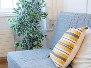 A room with a bed, a striped pillow, and a potted plant. - Apartment  by Interhome (Zurich)