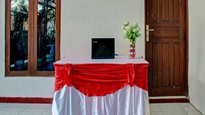 Une table avec un ordinateur portable, un vase rempli de fleurs et une nappe rouge et blanche.