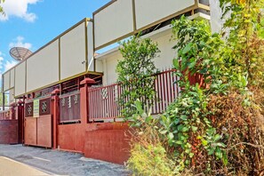 Zona residencial privada con cerramiento, antena parabólica, cerca roja y vegetación descuidada.