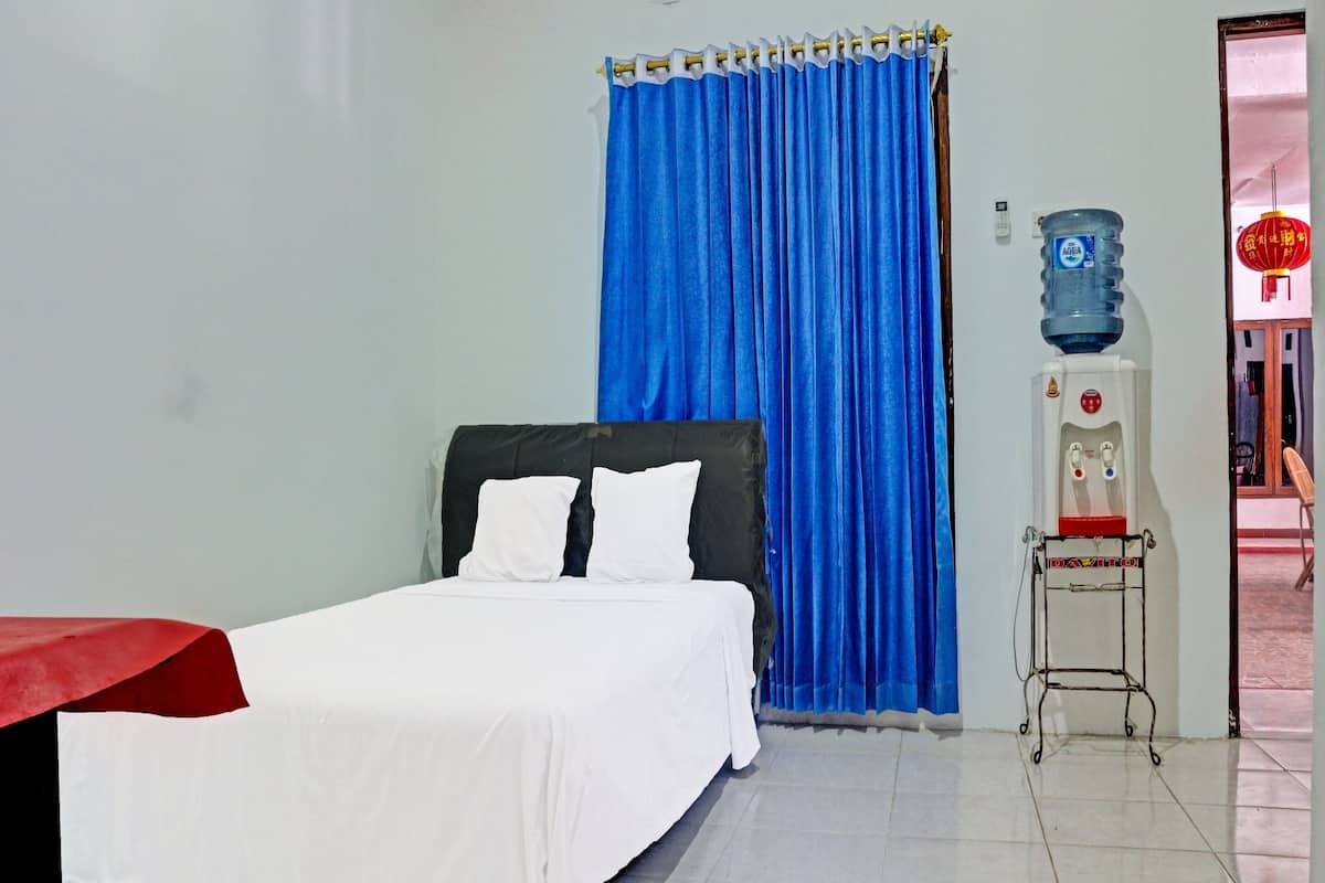 A hotel room with a bed, a water dispenser, and a curtain.