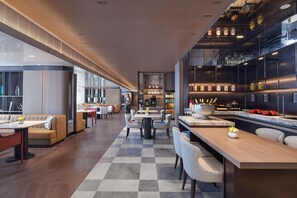 Un moderno vestíbulo de hotel con suelo de cuadros, zonas de estar y un bar con una barra larga.