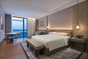 Habitación de hotel moderna con una cama grande, un escritorio, una silla y vistas a la ciudad.