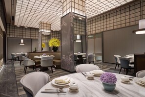 A modern dining area with tables, chairs, and a decorative vase. - Hyatt Regency Hangzhou Intl Airport (Hangzhou)
