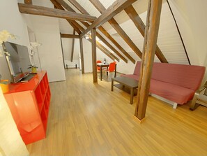 A loft-style room with wooden beams, a dining area with red chairs, and a red sofa. - ZH Strawberry - Oerlikon HITrental Apartment by Interhome (Zurich)