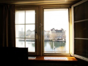 Ein Zimmer mit großem Fenster und Blick auf einen Fluss und Gebäude.