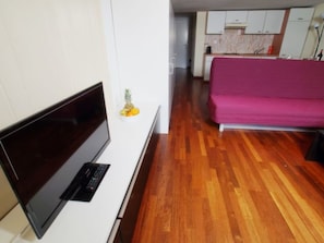 Ein modernes Wohnzimmer mit Flachbildfernseher, einem kleinen Tisch und einer Couch.