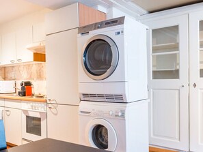 Una cocina compacta con lavadora y secadora apiladas, un microondas y una estufa.