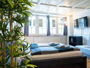 A hotel room with a bed, a TV, and a window with curtains. - Apartment  by Interhome (Zurich)
