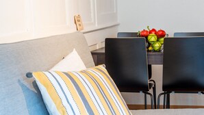 Ett modernt vardagsrum med en grå soffa, en randig kudde och ett matbord med stolar.