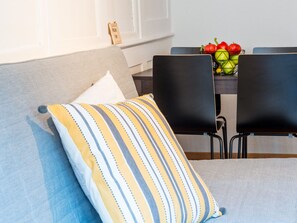 A modern living room with a grey sofa, a striped pillow, and a dining table with chairs. - Apartment  by Interhome (Zurich)