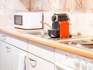 A kitchen with a microwave, a coffee maker, and a stove. - Apartment  by Interhome (Zurich)