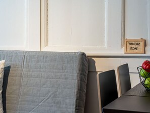 A room with a grey sofa, a small table with a bowl of fruit, and a 'Welcome Home' sign on the wall. - Apartment  by Interhome (Zurich)