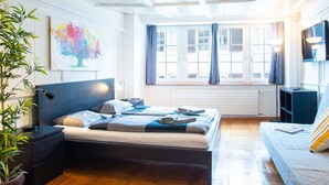 A modern bedroom with a bed, bedside tables, a TV, and a window with curtains.