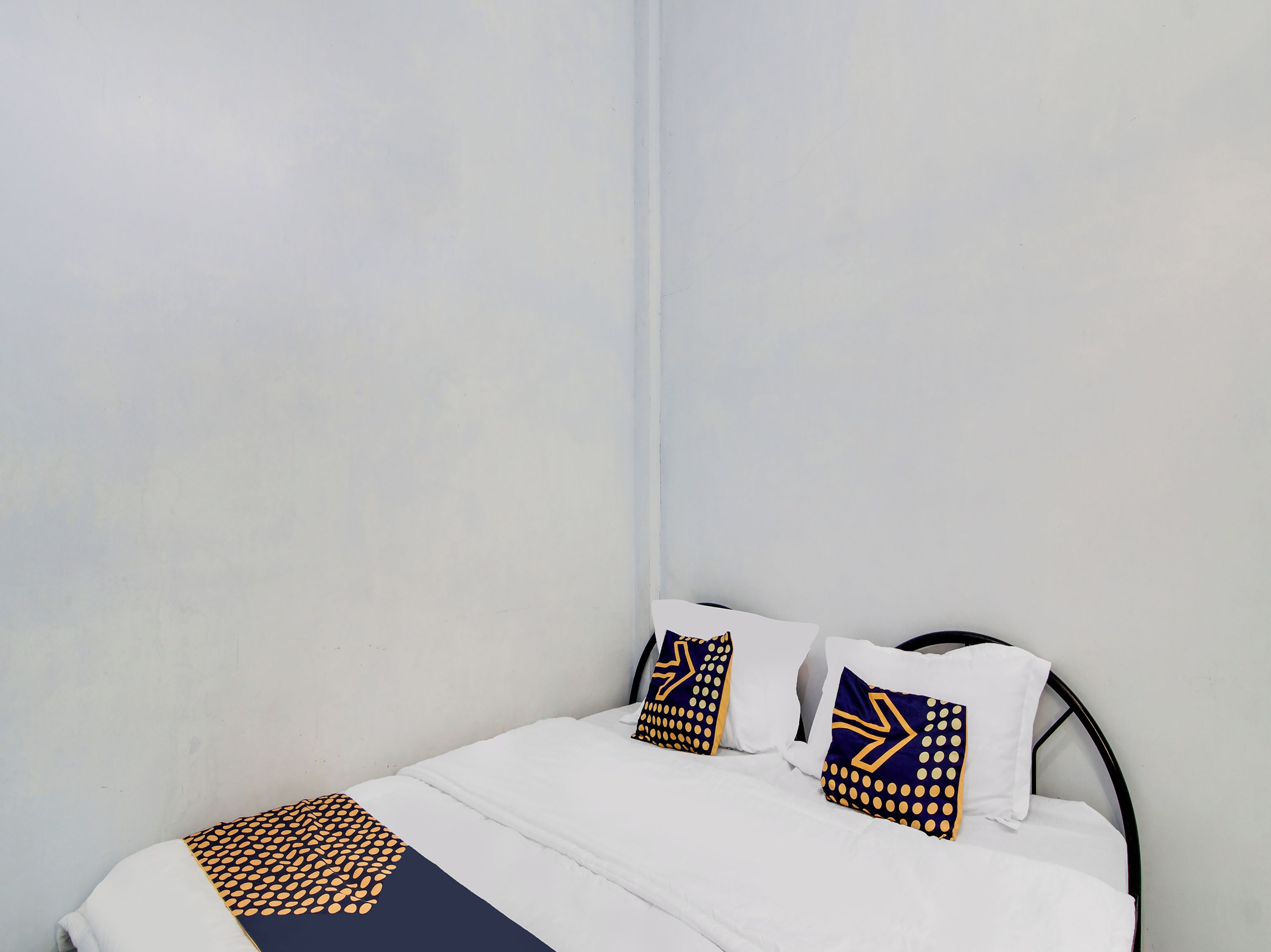 A neatly made bed with white bedding and two decorative pillows with geometric patterns.
