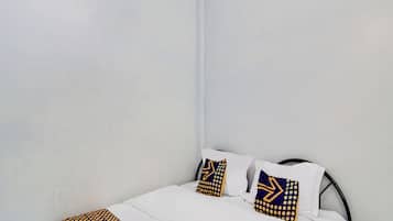 A neatly made bed with white bedding and two decorative pillows with geometric patterns.