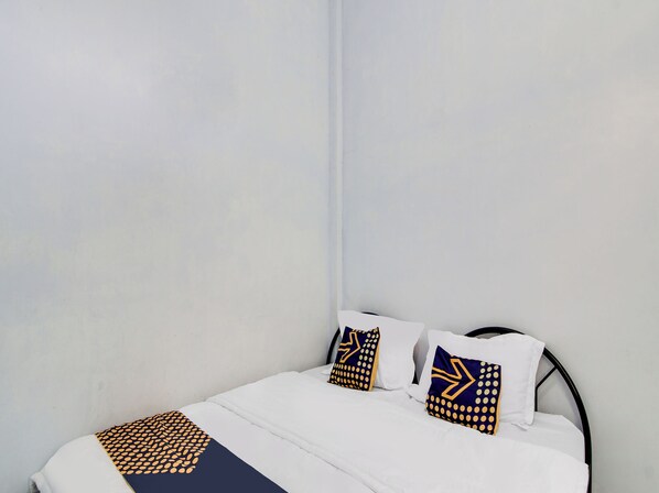 Una cama bien tendida con ropa blanca y dos almohadas decorativas con diseños geométricos.