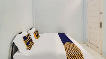 A bed with white bedding, two pillows with yellow and blue patterns, and a blue and yellow striped blanket.