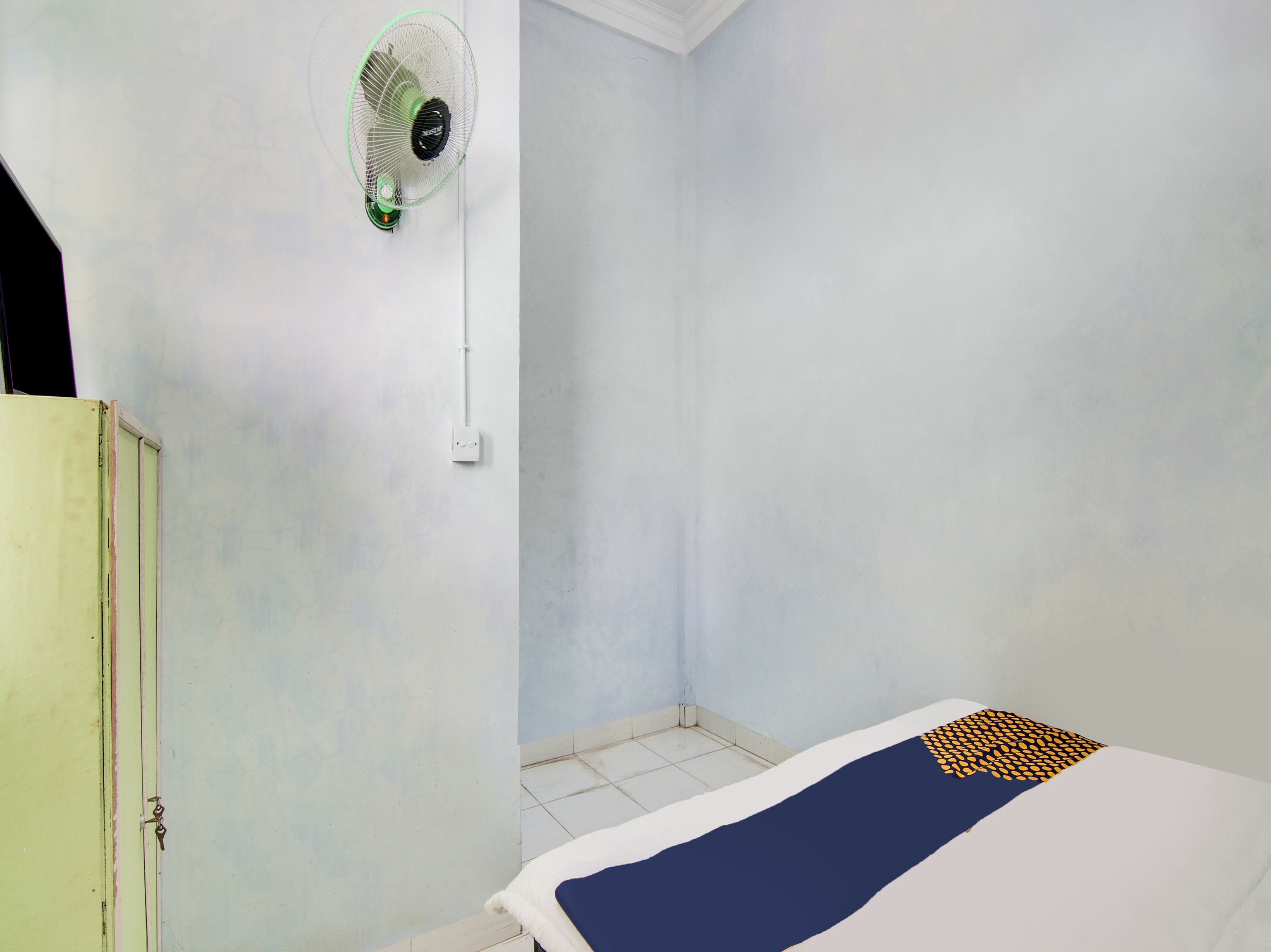 Ein Zimmer mit einem Bett, einem Wandventilator und einer Tür.