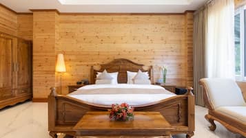 A bedroom with a wooden headboard bed, a wooden nightstand, a lamp, a wooden cabinet, and a chair.
