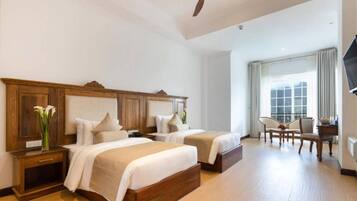 A hotel room with two beds, a desk, a chair, and a large window.