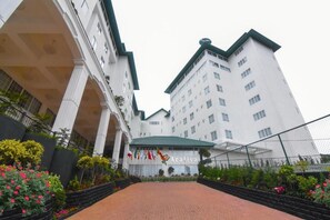A hotel with a central courtyard, multiple flags, and a prominent entrance. - Araliya Red (Nuwara Eliya)