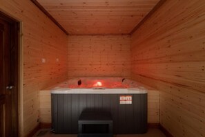 Un sauna de madera con bañera de hidromasaje y un banco.