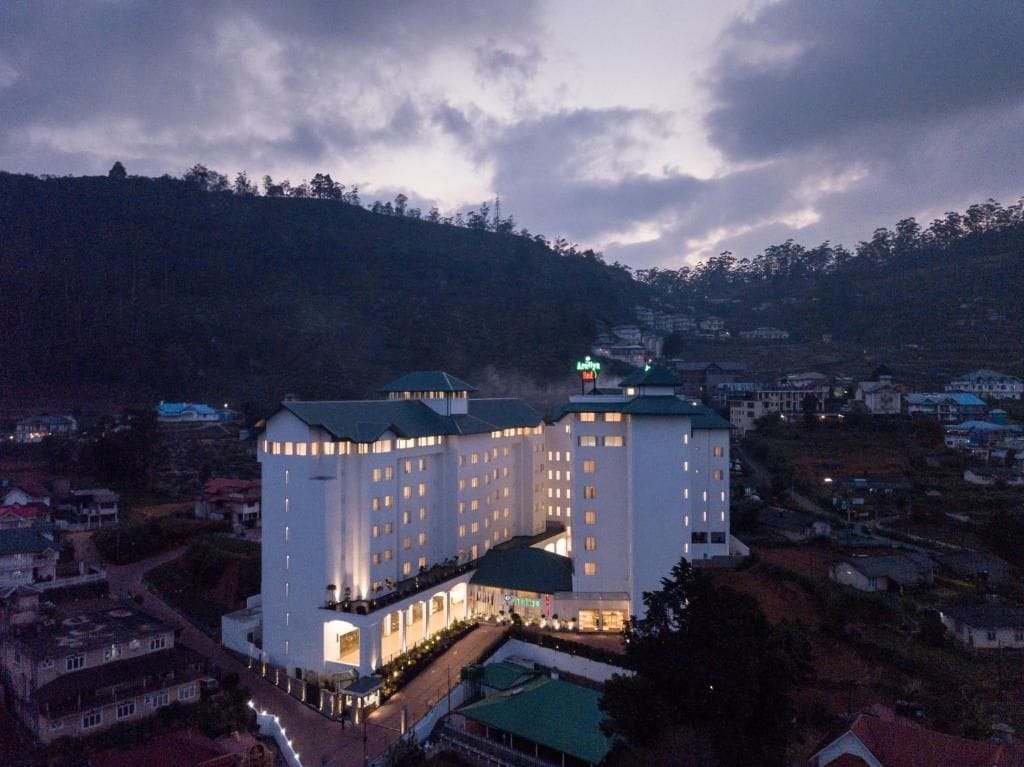 A large, multi-story hotel with a central courtyard, surrounded by a hilly landscape.