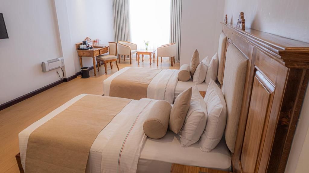 Une chambre d’hôtel avec deux lits, un bureau et une chaise.
