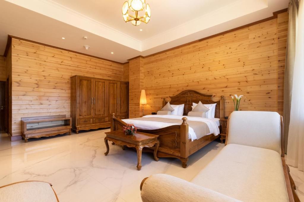 Une chambre à coucher avec un lit doté d’une tête de lit en bois, une armoire en bois, une table de chevet avec une lampe et une chaise.