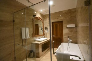 A modern bathroom with a glass shower enclosure, a standalone bathtub, and a vanity with a mirror. - Araliya Red (Nuwara Eliya)