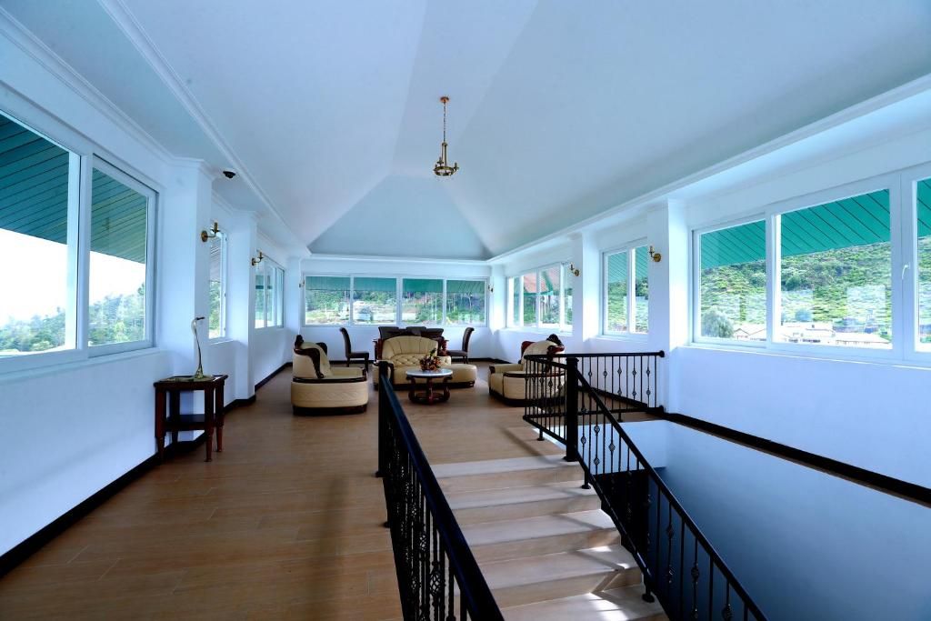 A spacious hallway with a staircase, large windows, and a chandelier.