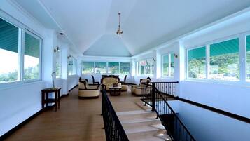 A spacious hallway with a staircase, large windows, and a chandelier.