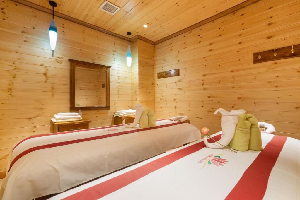 Ein Zimmer mit Holzwänden, zwei Betten, einem Holzschrank und einem Spiegel an der Wand.