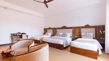 A hotel room with two beds, a wooden headboard, a ceiling fan, a wooden side table, and a chair.