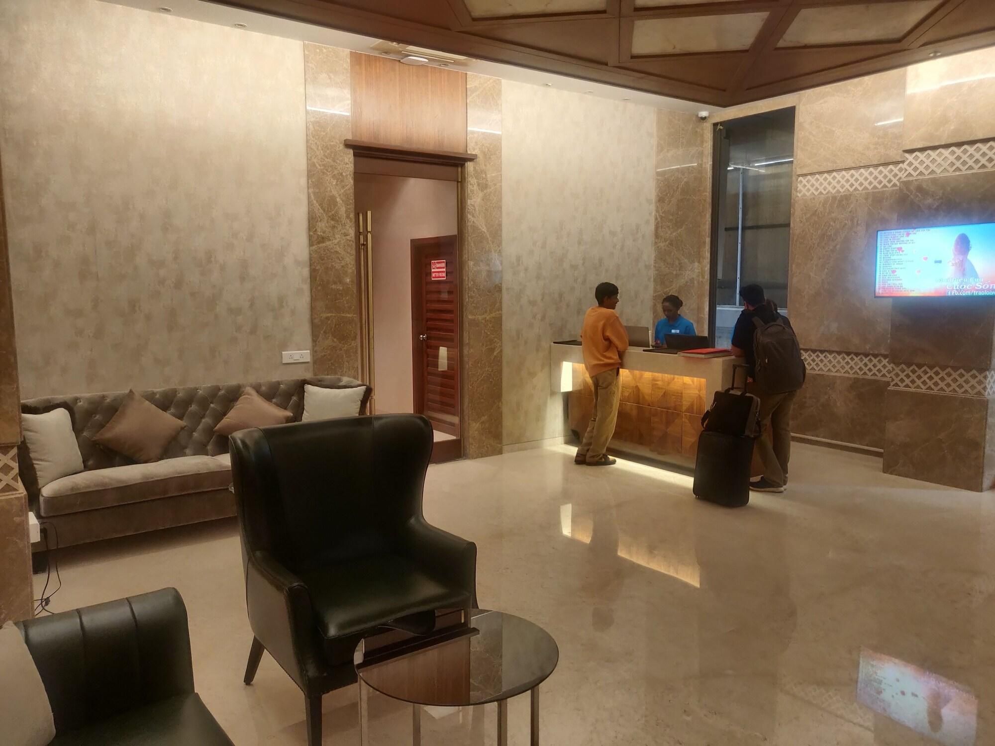 Eine Hotlellobby mit einer Rezeption, einer Couch, einem schwarzen Sessel und einem Glastisch.