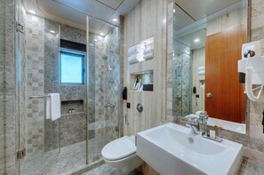 A modern bathroom with a glass-enclosed shower, a large white sink, and a wooden door. - Adiva Residency Beacon,mumbai (Mumbai)