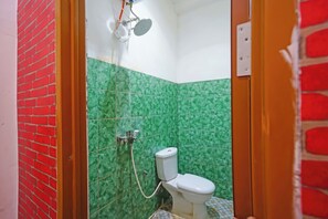 Casa de banho com chuveiro, sanita e azulejos estampados.
