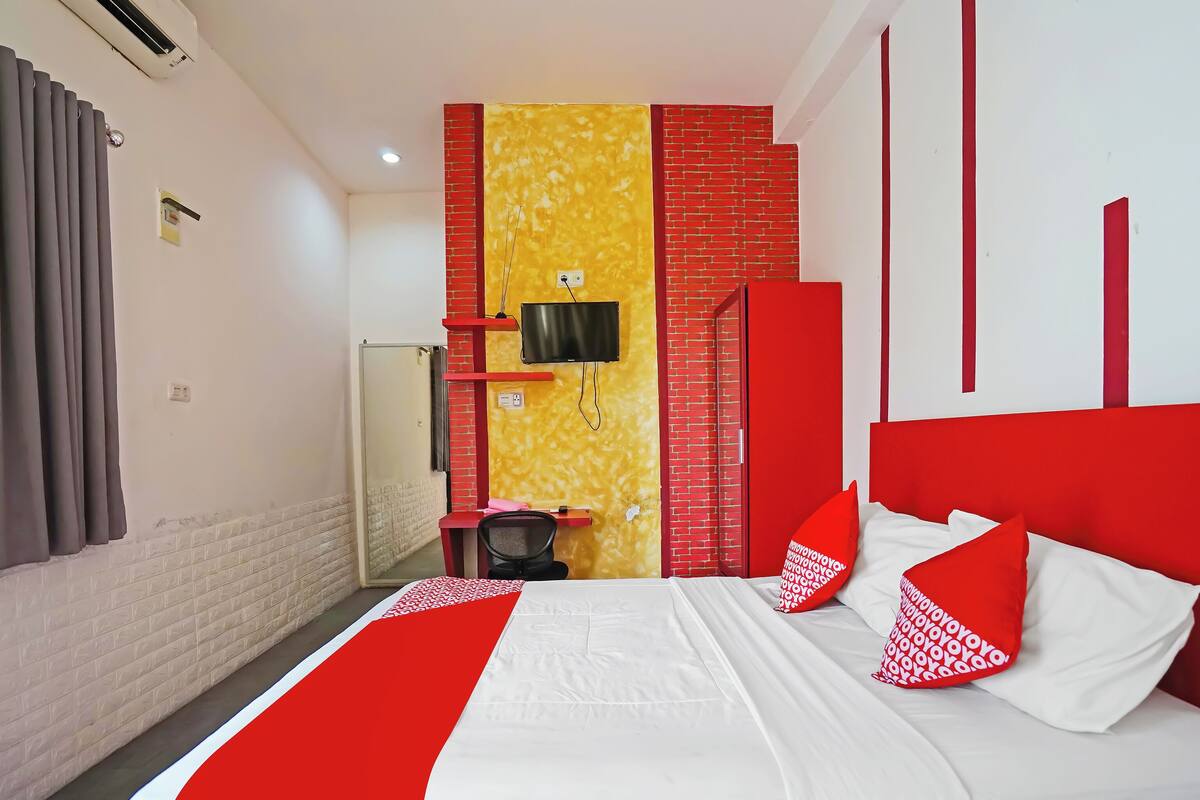 Een hotelkamer met een bed, televisie, bureau en stoel.