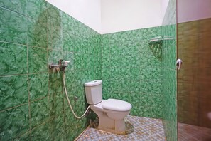 Un baño con azulejos de mármol verde, un inodoro blanco y una zona de ducha.