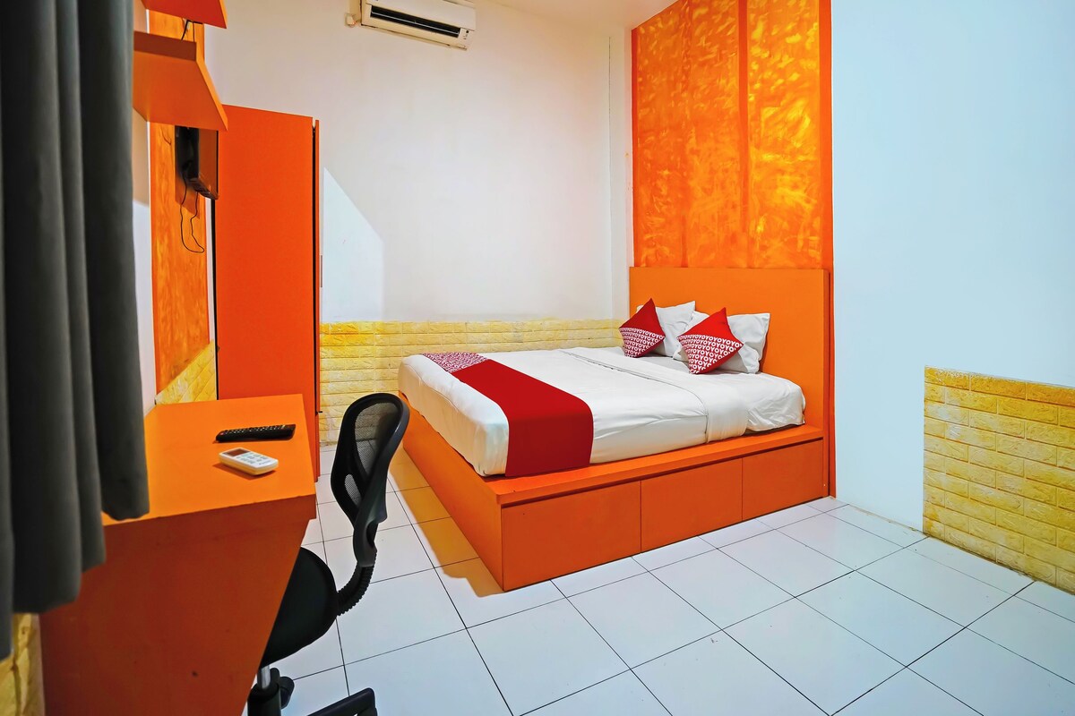 Una habitación de hotel con cama, escritorio, silla y aire acondicionado.